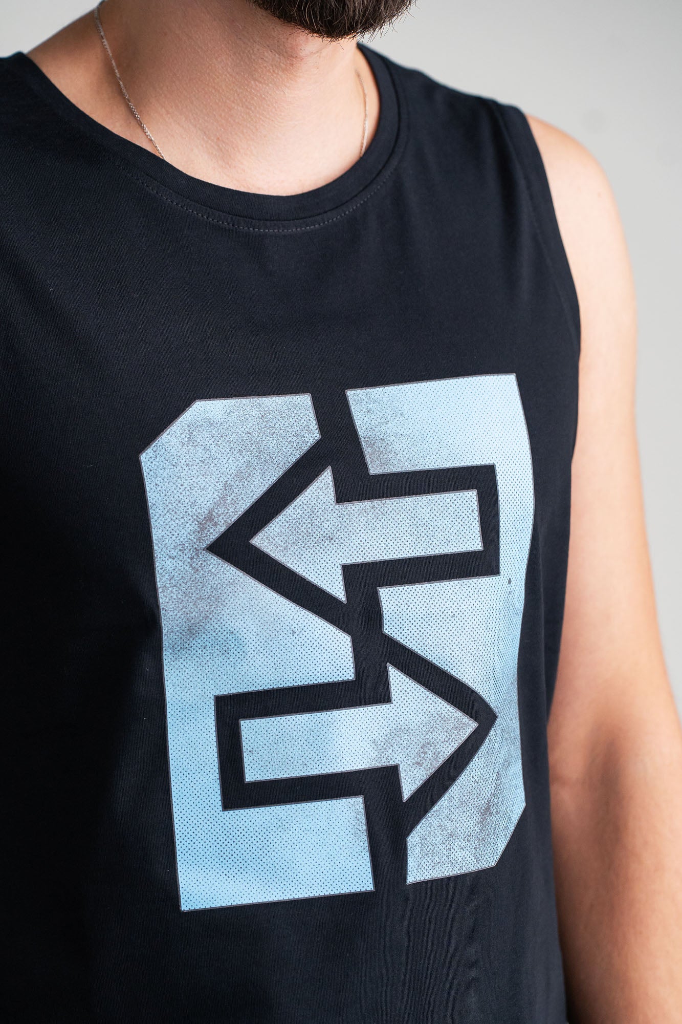 Ein Mann trägt ein Tanktop mit Logo, symbolisiert Stärke und Frische, bereit für Abenteuer und Herausforderungen.