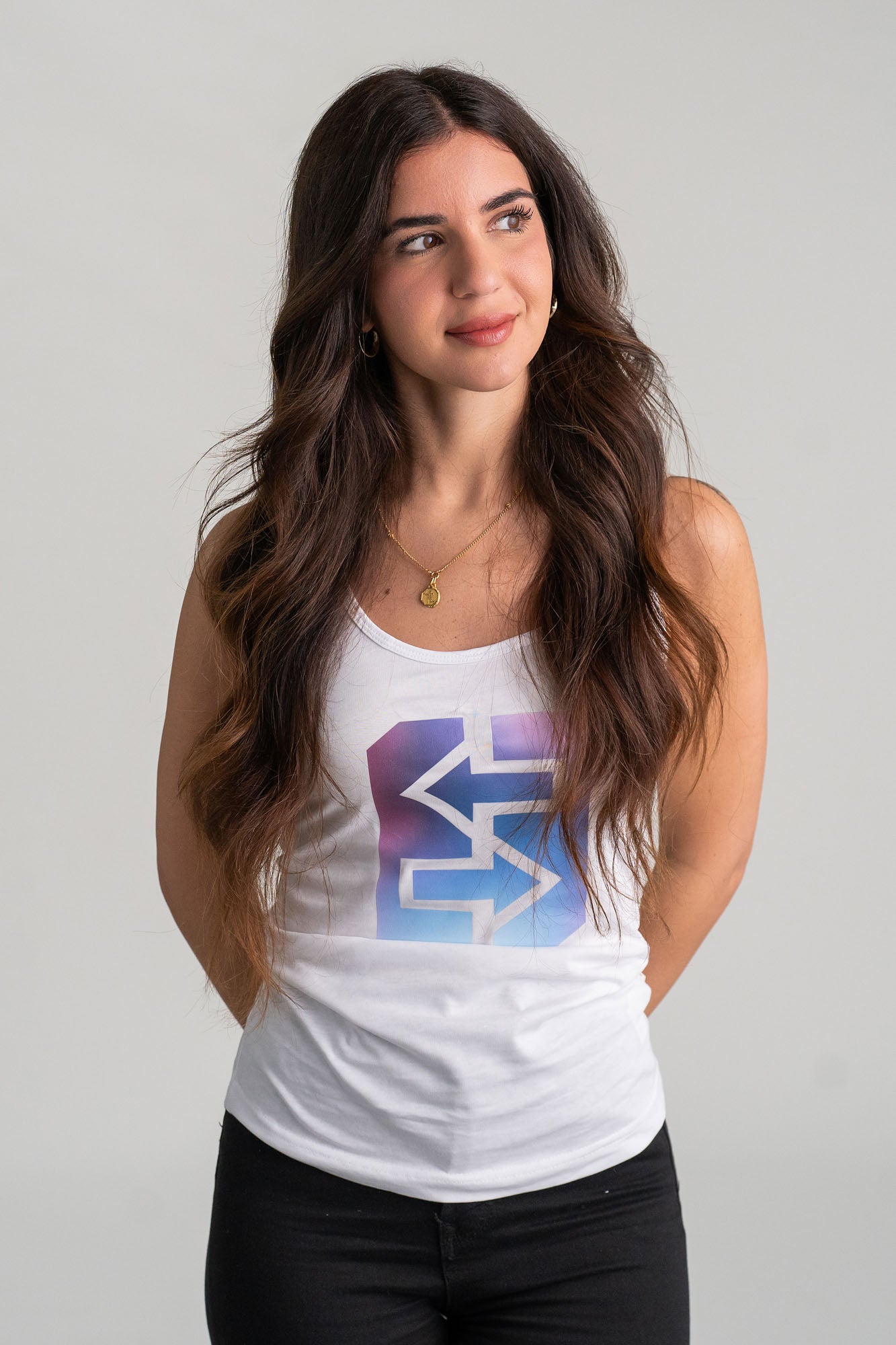 Eine Frau trägt ein weißes Tanktop mit blau-lila Logo, ideal für sonnige Tage am Strand oder in der Stadt.
