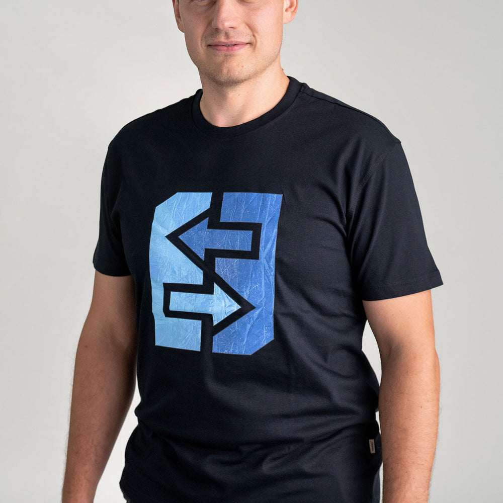 Ein Mann trägt ein schwarzes T-Shirt mit einem blauen Logo, das frischen Wind und nordische Coolness symbolisiert.