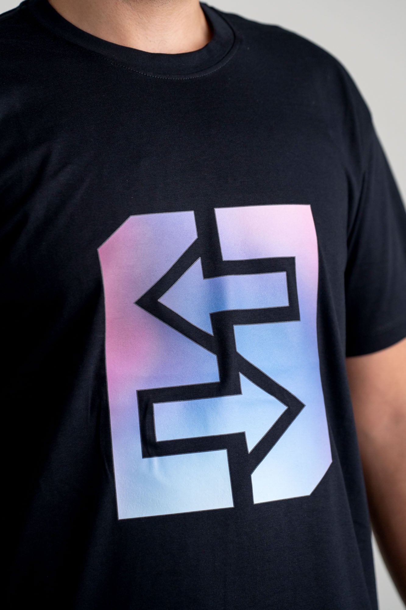 Ein lächelnder Mann trägt ein schwarzes T-Shirt mit lila-blauem Logo, das den Miami-Lifestyle verkörpert.