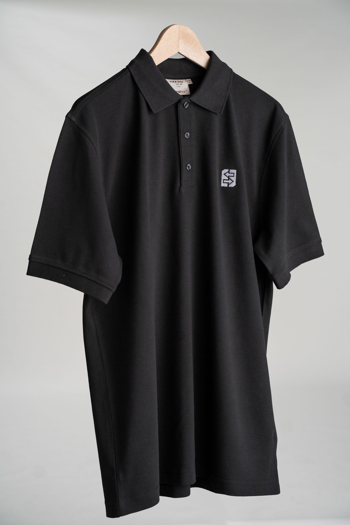 Schwarzes Poloshirt mit weißem LANG-Logo auf der Brust, ideal für Büro und Freizeit, vereint Stil und Funktionalität.