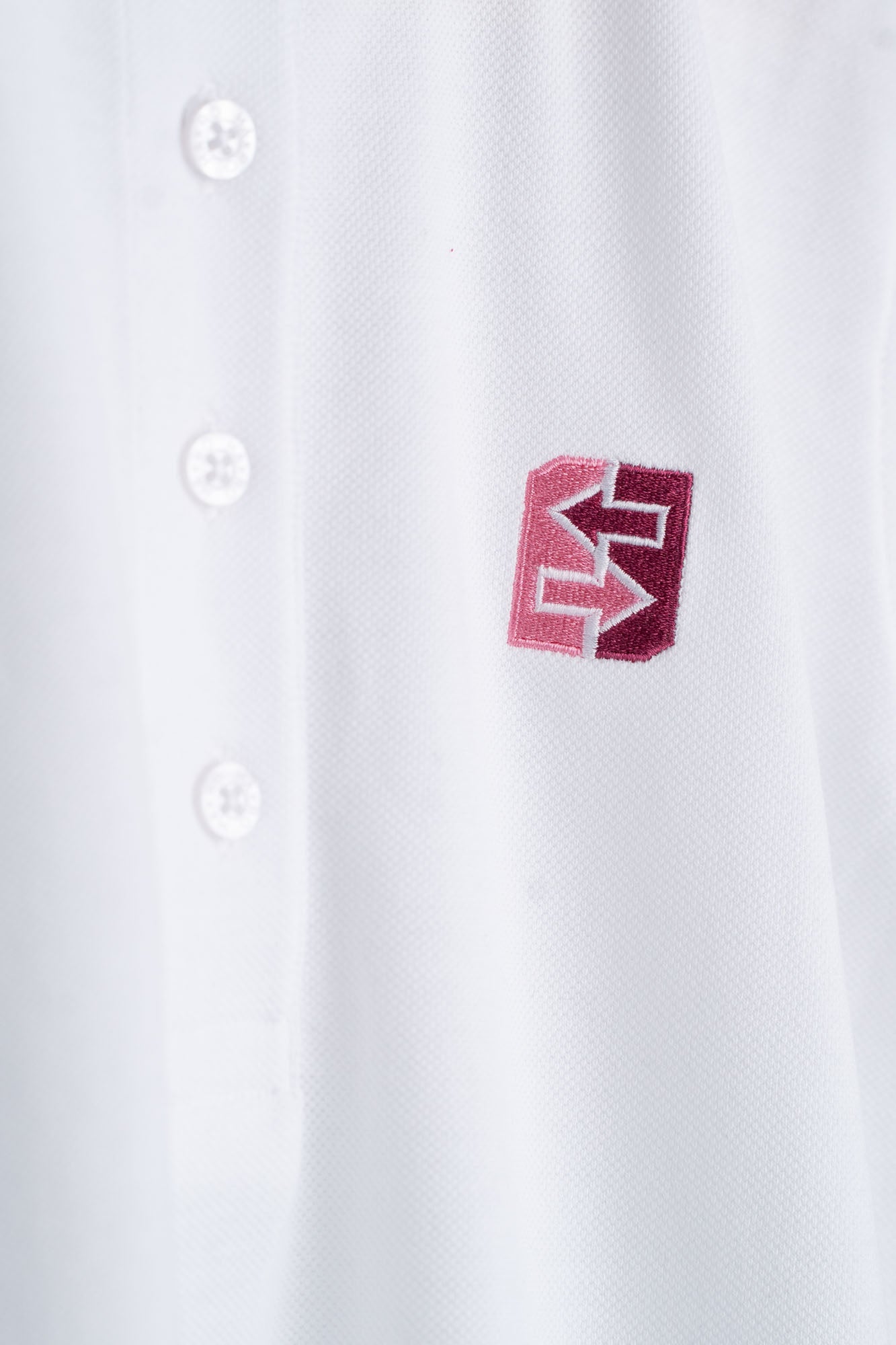Nahaufnahme eines weißen Polohemds mit rotem Logo, ideal für Freizeit und Büro, vereint Stil und Funktionalität.